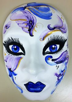 a white mask with blue and purple flowers painted on it's face to resemble a woman's face