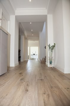 an empty living room with wood floors and white walls is pictured in this image from the hallway to the kitchen