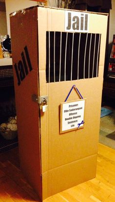 an open cardboard box with a jail sign on the front and door is sitting on top of a hard wood floor