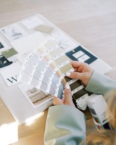 a person is holding some paint samples on a table