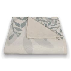 a white blanket with green leaves on it