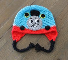 there is a crocheted hat with a train on the front and blue, red, and white stripes