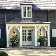 a house with two potted plants on the front porch and an entry way leading to it