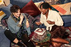 two women sitting on a couch next to a cake