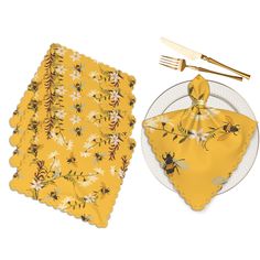 a yellow napkin with bees on it next to a plate and utensil holder