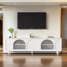 a flat screen tv mounted to the side of a white cabinet in a living room