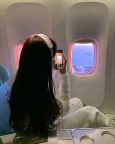 a woman sitting on an airplane looking out the window