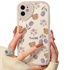 a woman holding up her phone case with flowers and hearts on the back, while wearing rings