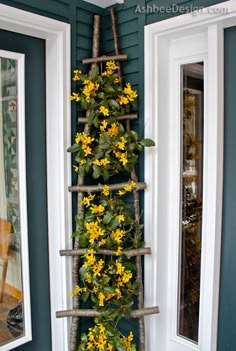 a ladder made out of branches with flowers growing on it and two windows in the background