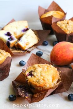 muffins with blueberries and peaches are on the table next to some fruit