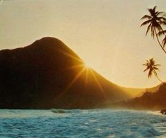 the sun shines brightly over an ocean with palm trees and mountains in the background