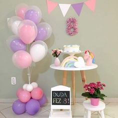 a table topped with lots of balloons next to a cake