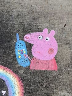 a chalk drawing of peppa the pig holding a phone next to a rainbow drawn on concrete