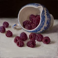 a painting of raspberries spilled out of a blue and white bowl on a table