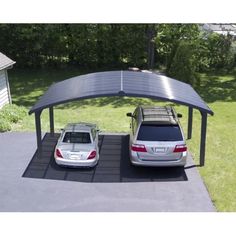 two cars parked under a metal carport in a driveway with grass and trees behind them