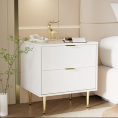 a white dresser sitting next to a bed with a plant on top of it in a room