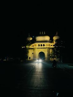 a person riding a motorcycle at night in front of a large building with domes on it