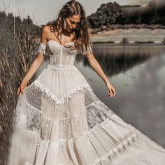 a woman in a white dress is standing by the water