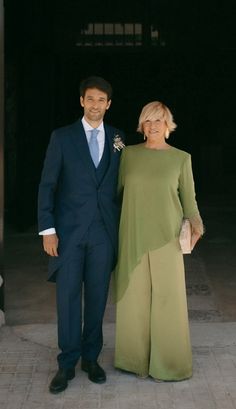 a man and woman standing next to each other in front of a doorway wearing formal attire