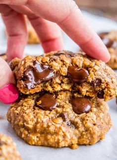 a hand picking up a chocolate chip cookie