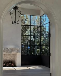 an arch leading into a room with a fireplace in the center and large windows on both sides