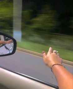 a person's hand on the side mirror of a car as it drives by