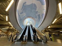 an escalator in a building with people on it and a map hanging from the ceiling