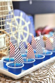 there are many small sailboats on the trays with blue cups in front of them