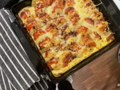 a casserole dish with sausage, tomatoes and cheese in it sitting on a table