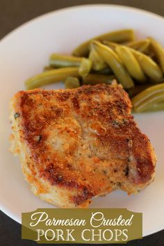 pork chops and green beans on a white plate with the words parmesan crusted pork chops