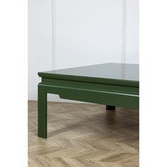 a green coffee table sitting on top of a hard wood floor next to a white wall