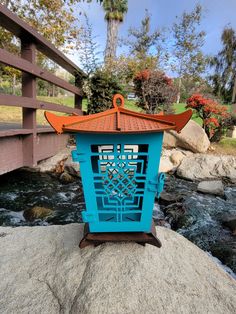 a blue lantern sitting on top of a rock next to a river