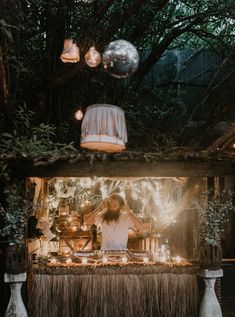 a man standing in front of a bar with lights on it and decorations hanging from the ceiling