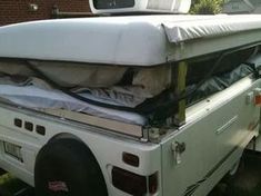 the back end of a white truck with a mattress on it's flatbed