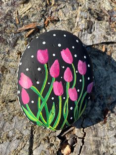 a painted rock with pink flowers on it