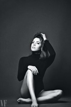 a black and white photo of a woman sitting on the floor with her hands behind her head