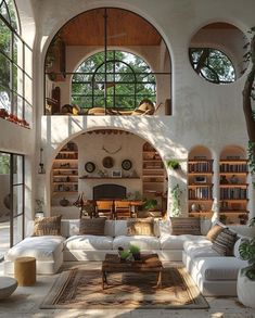 a living room filled with white furniture and lots of bookshelves on the wall