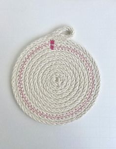 a white round rug with pink trim on the bottom and red stitching around it