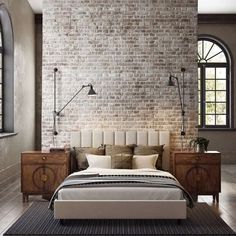 a bedroom with a brick wall, bed and nightstands in front of the window