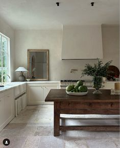 there is a bowl of fruit on the table in the middle of the kitchen area