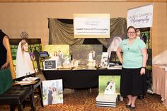 a woman standing in front of a table with pictures on it and other items for sale