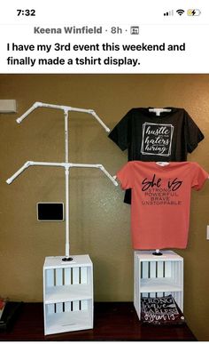 two t - shirts on display in front of a brown wall with white shelves and an ironing board attached to it