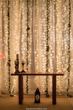 a table with two candles on it in front of a curtained wall and lights