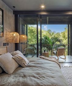 a bedroom with a large bed and glass doors leading to an outside deck area that overlooks the trees