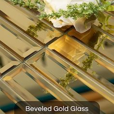 a glass table with flowers in it and the words beveled gold glass on top