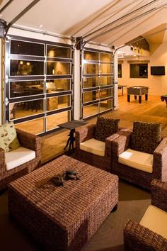 a living room with wicker furniture and large windows on the wall, along with wooden flooring