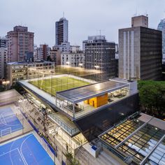 an aerial view of a tennis court in the middle of a city at night with lots of tall buildings