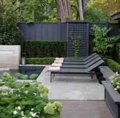 an outdoor patio area with lounge chairs and flowers in the foreground, surrounded by greenery