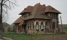 an old, run down house in the middle of a field with trees and grass