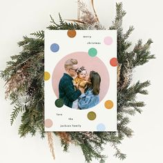 a christmas card with an image of a man and woman holding a baby in front of them